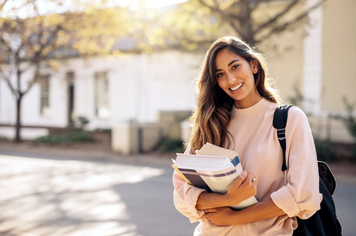 happy university student holding textbooks