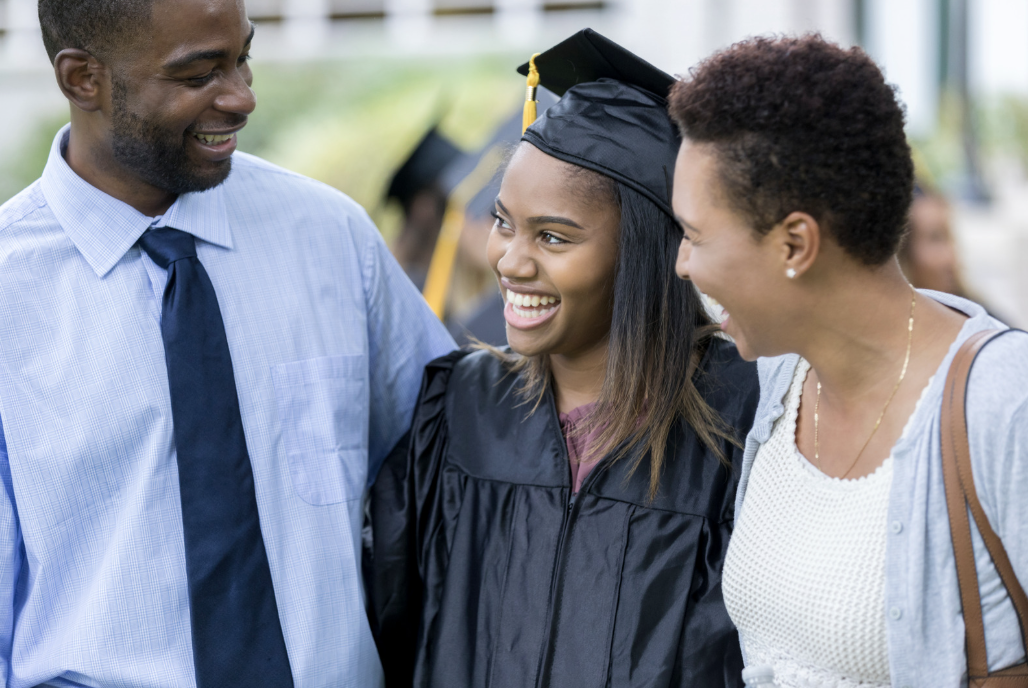 Happy high school girl with proud parents at graduation