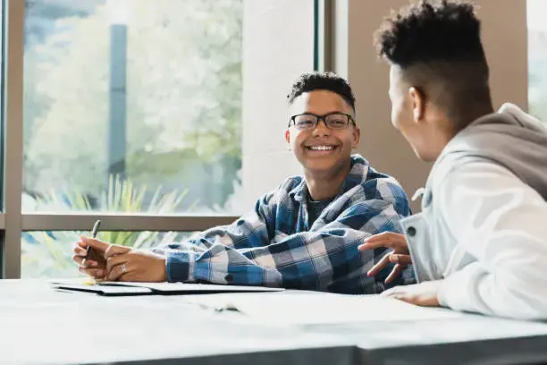 A high school student smiles at mentor.